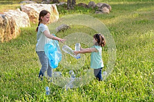 Kids cleaning in park.Volunteer children with a garbage bag cleaning up litter, putting plastic bottle in recycling bag.