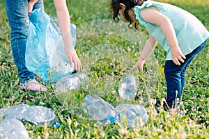 Kids cleaning in park.Volunteer children with a garbage bag cleaning up litter, putting plastic bottle in recycling bag.