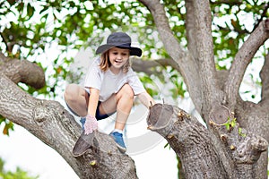 Kids climb tree in summer park. Child climbing