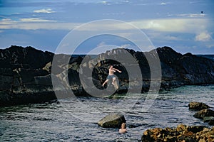 Kids climbing rock wall at The Tanks tourist attraction natural rock pool at Forster, New South Wales Australia