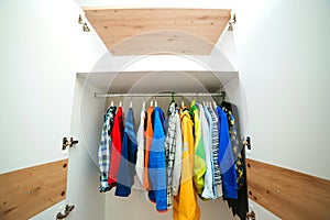 Kids clothing on the hangers. White modern closet inside. Storage organization. Order and cleanliness