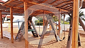 Kids club and playground with slide and swing under wooden pergola  in egyptian hotel