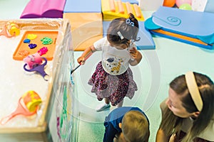 kids coloring the cellophane in kindergarten, creative activities for preschoolers toys in the background