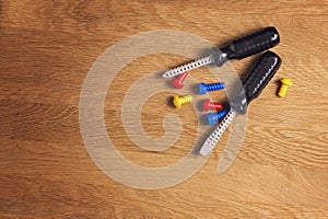 Kids construction toys tools: colorful screwdrivers, screws and nuts on wooden background. Top view. Flat lay. Copy