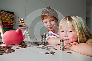 Kids count and save money, girl and boy put coins into piggy bank