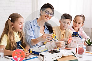 Kids creating robots with teacher at stem education class