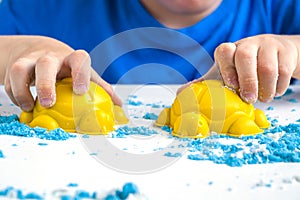 Kids creativity. Kinetic sand games for child development at home. Sand therapy. Children`s hands making moldes. Selective focus,