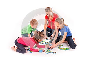 Kids of different age solving jigsaw puzzle together