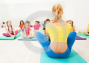 Kids doing butterfly stretch with female coach