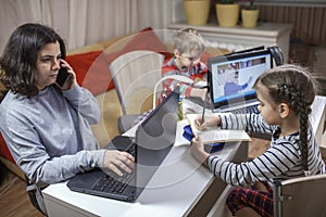 Kids doing homework and mother working online in one room, distant education at home