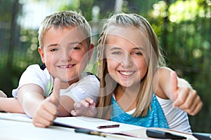 Kids doing thumbs up at desk.