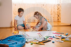 Kids drawing on floor on paper. Preschool boy and girl play on floor with educational toys - blocks, train, railroad