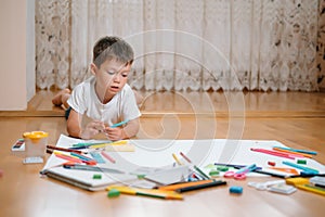 Kids drawing on floor on paper. Preschool boy and girl play on floor with educational toys - blocks, train, railroad, plane. Toys