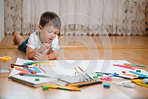 Kids drawing on floor on paper. Preschool boy and girl play on floor with educational toys - blocks, train, railroad, plane. Toys