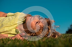 Kids dreaming. Happy little boy laying on grass. Kids exploring nature, summertime.