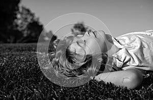 Kids dreaming. Kid playing in the meadow. Happy healthy caucasian child boy with lying on the grass field background