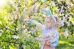 Kids on Easter egg hunt in blooming garden.