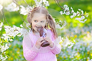 Kids on Easter egg hunt in blooming garden.