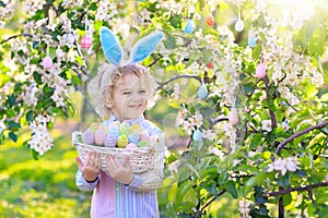 Kids on Easter egg hunt in blooming garden.