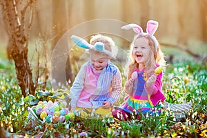 Kids on Easter egg hunt in blooming spring garden.