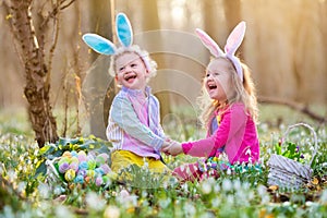 Kids on Easter egg hunt in blooming spring garden