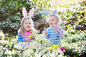Kids on Easter egg hunt in blooming spring garden
