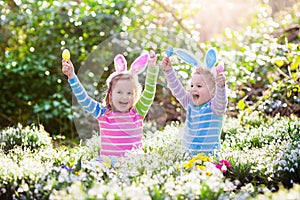 Kids on Easter egg hunt in blooming spring garden