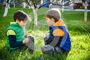 Kids on Easter egg hunt in blooming spring garden. Children searching for colorful eggs in flower meadow. Toddler boy and his