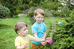 Kids on Easter egg hunt in blooming spring garden. Children searching for colorful eggs in flower meadow. Toddler boy and his brot