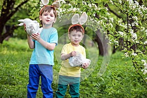 Kids on Easter egg hunt in blooming spring garden. Children searching for colorful eggs in flower meadow. Toddler boy and his brot