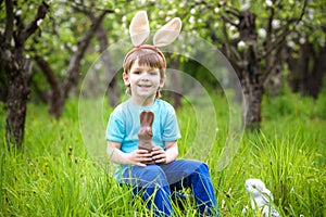 Kids on Easter egg hunt in blooming spring garden. Children searching for colorful eggs in flower meadow. Toddler boy and his brot