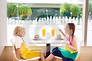 Kids eat cake at restaurant. Boy and girl in cafe.