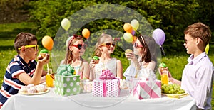Kids eating cupcakes on birthday party in summer