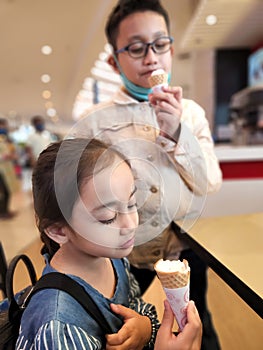 Kids Eating Ice-Cream at the mall. Little girl and big brother enjoying desserts