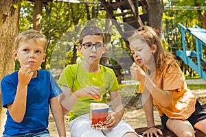 The kids are eating popcorn together in the park