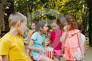 The kids are eating popcorn together in the park