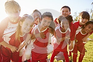 Kids in elementary school sports team piggybacking outdoors