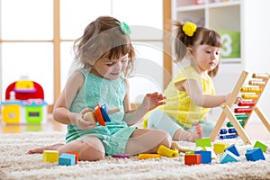 Kids are engaging in daycare. Two toddler children playing with educational toys in kindergarten.