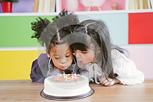 Kids enjoying a birthday party blowing out the candle on cake.