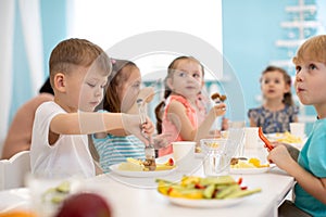 Kids enjoying healthy lunch in kindergarten