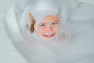 Kids face in foam. Kid having fun in the bath with bubbles. Happy child enjoying bath time. Little boy smiling in the