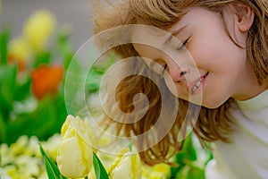 Kids face in tulips. Happy spring. Spring tulips and kid. Kid among tulips field in spring blossom park. Cute kids face