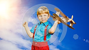 Kids fantasy. Child playing with toy airplane against sky and cl