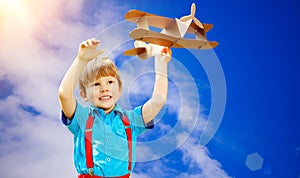 Kids fantasy. Child playing with toy airplane against sky and cl