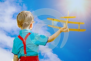 Kids fantasy. Child playing with toy airplane against sky and cl