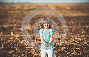 Kids farmer. American child on farm. Soil and ground concept. Textured fertile soil as background. Gardening season.