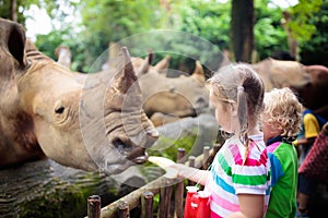 Kids feed rhino in zoo. Family at animal park