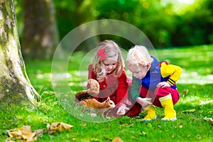 Kids feeding squirrel in autumn park