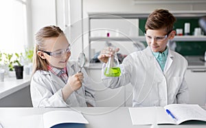 Kids with flask and magnifier at chemistry class