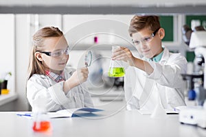 Kids with flask and magnifier at chemistry class